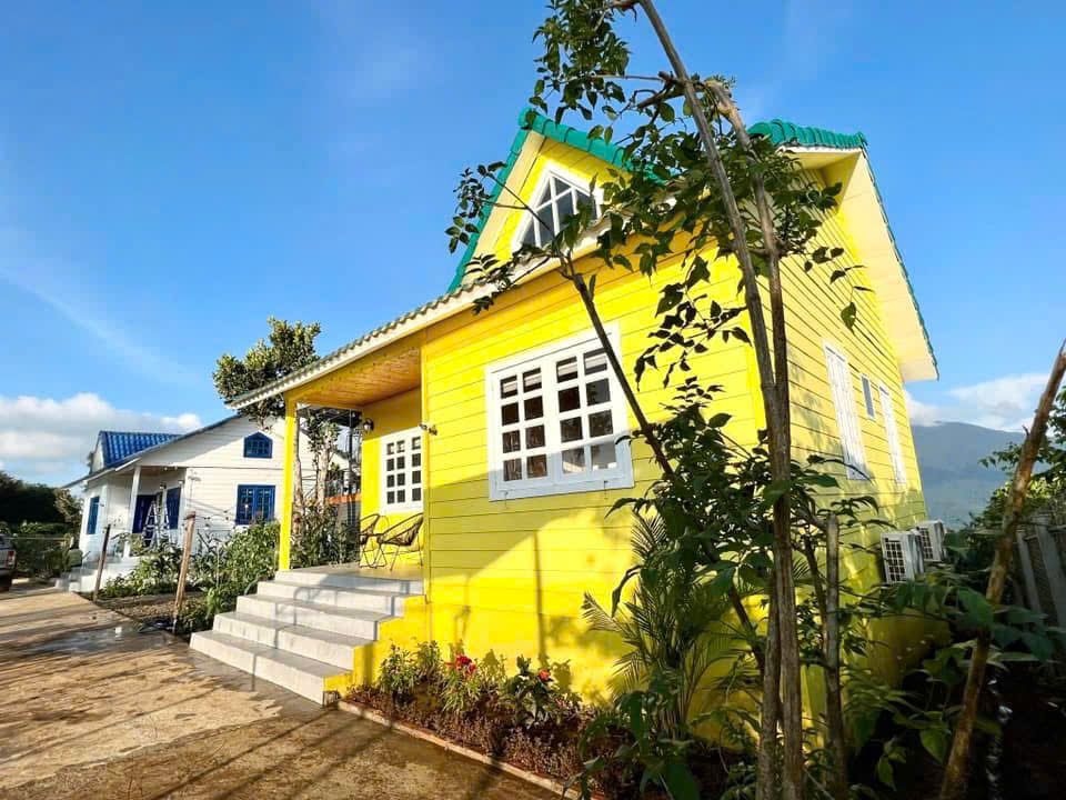 Căn nhà gỗ sơn vàng có hiên và bậc thềm trắng ở Tà Đùng